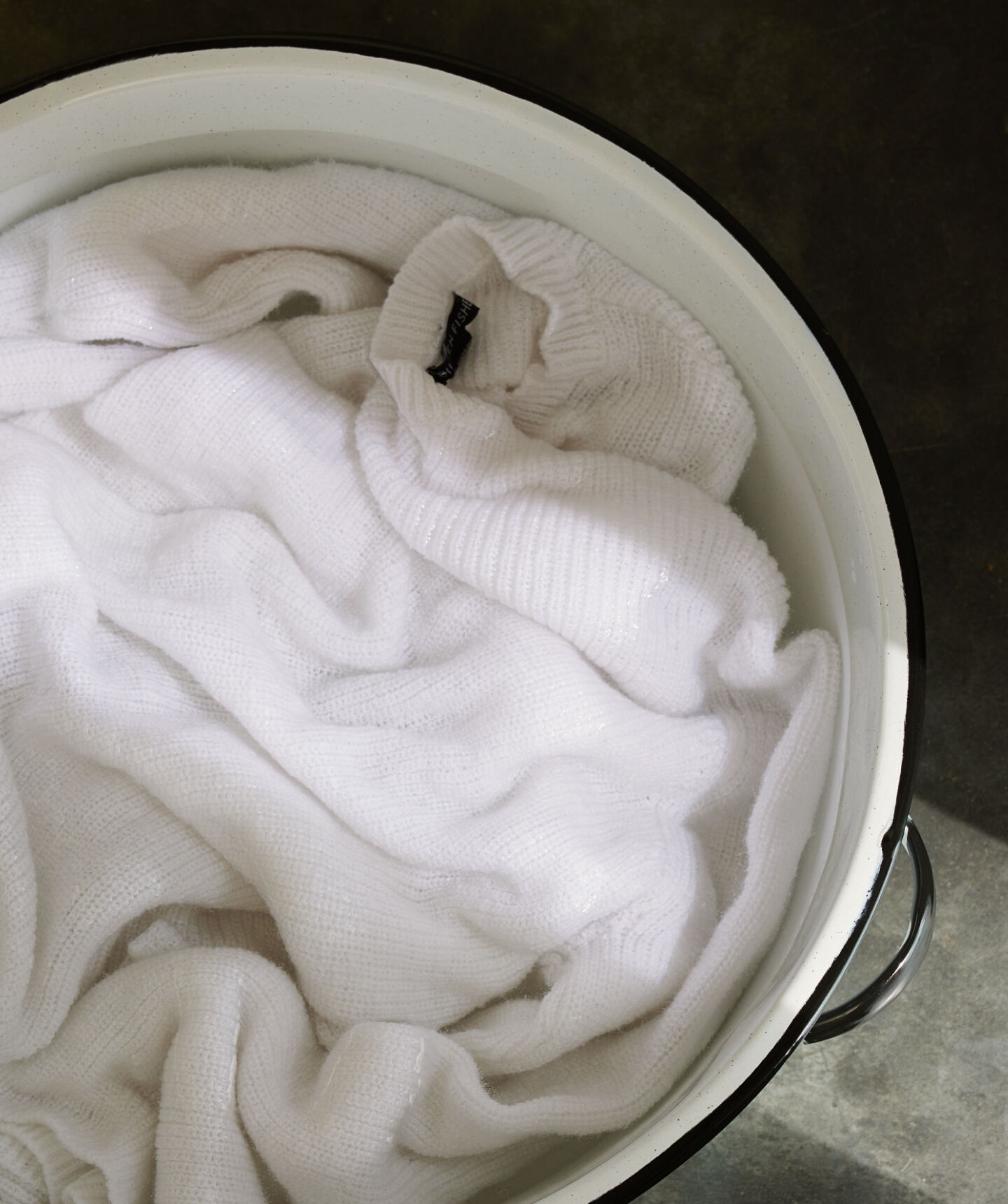 Beige sweater in basin of soapy water. Beige sweater in basin of soapy water.