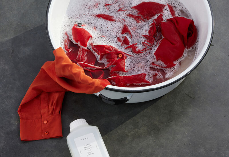 Orange silk shirt being hand washed in a basin.