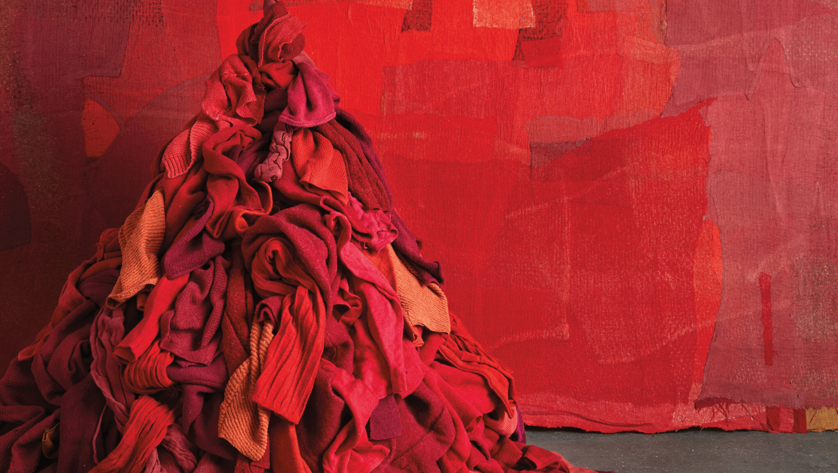 Red pile of EILEEN FISHER clothes against artful red backdrop. 