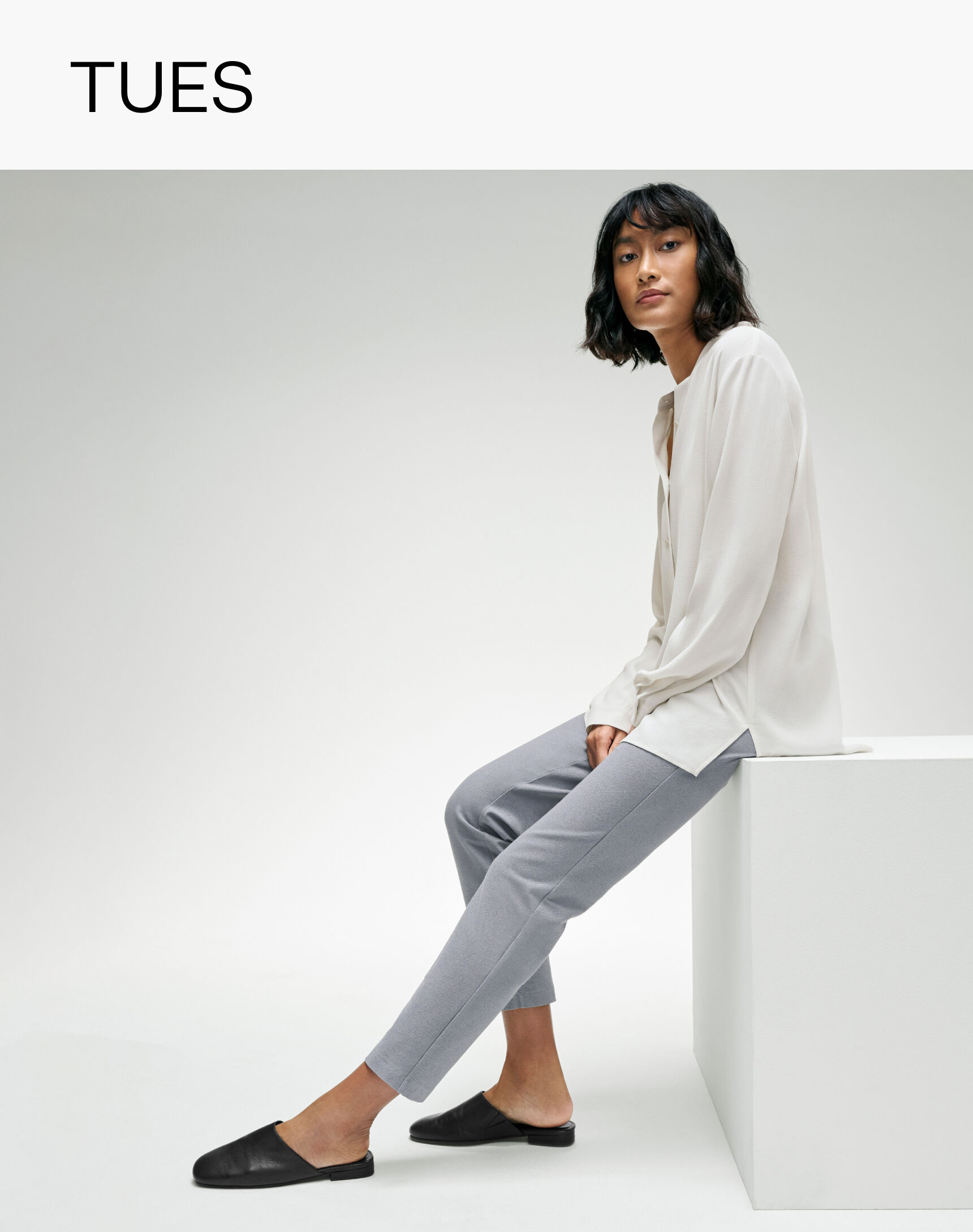 Seated woman wearing grey slim pants. 