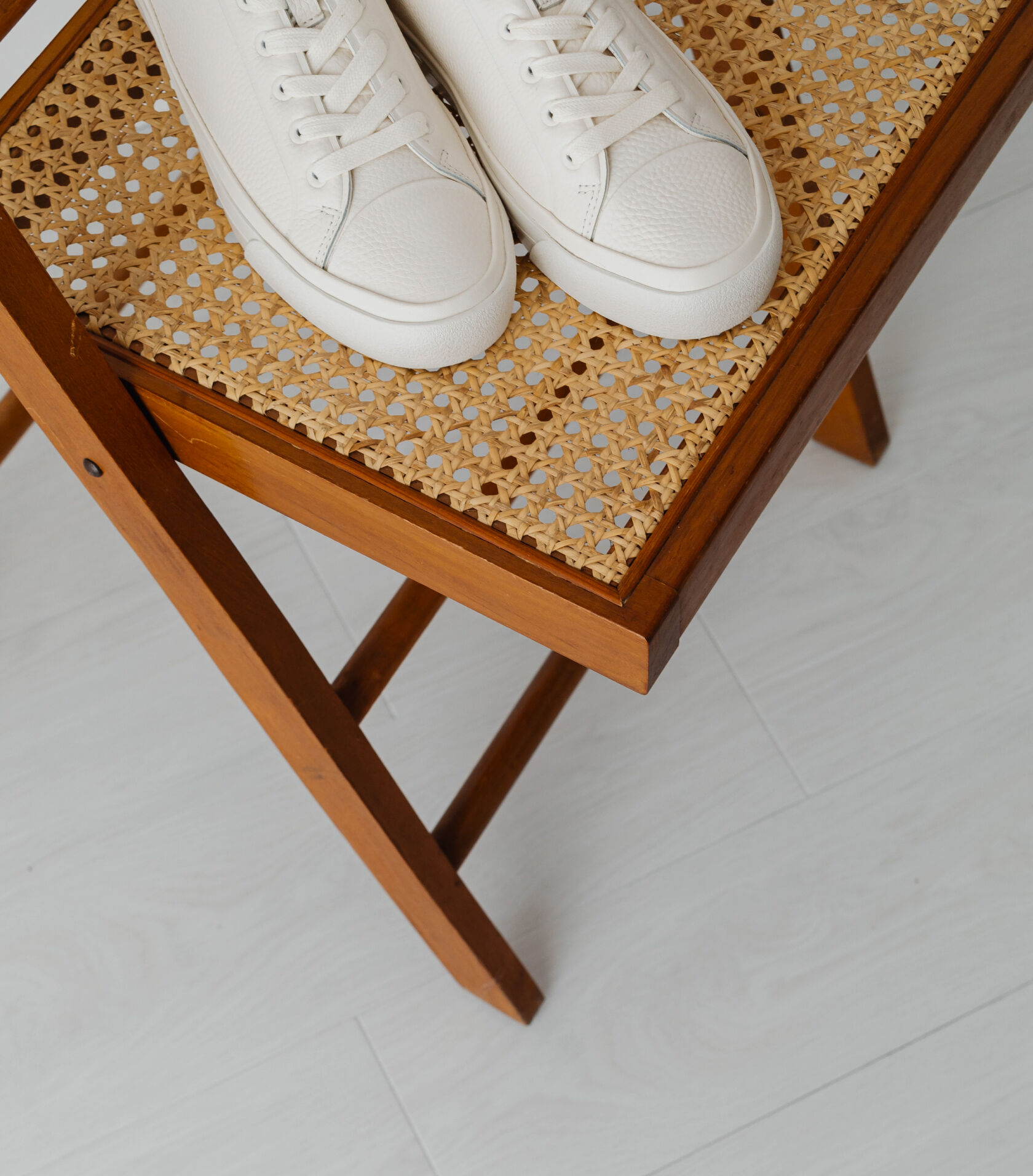 A pair of white sneakers on a chair.