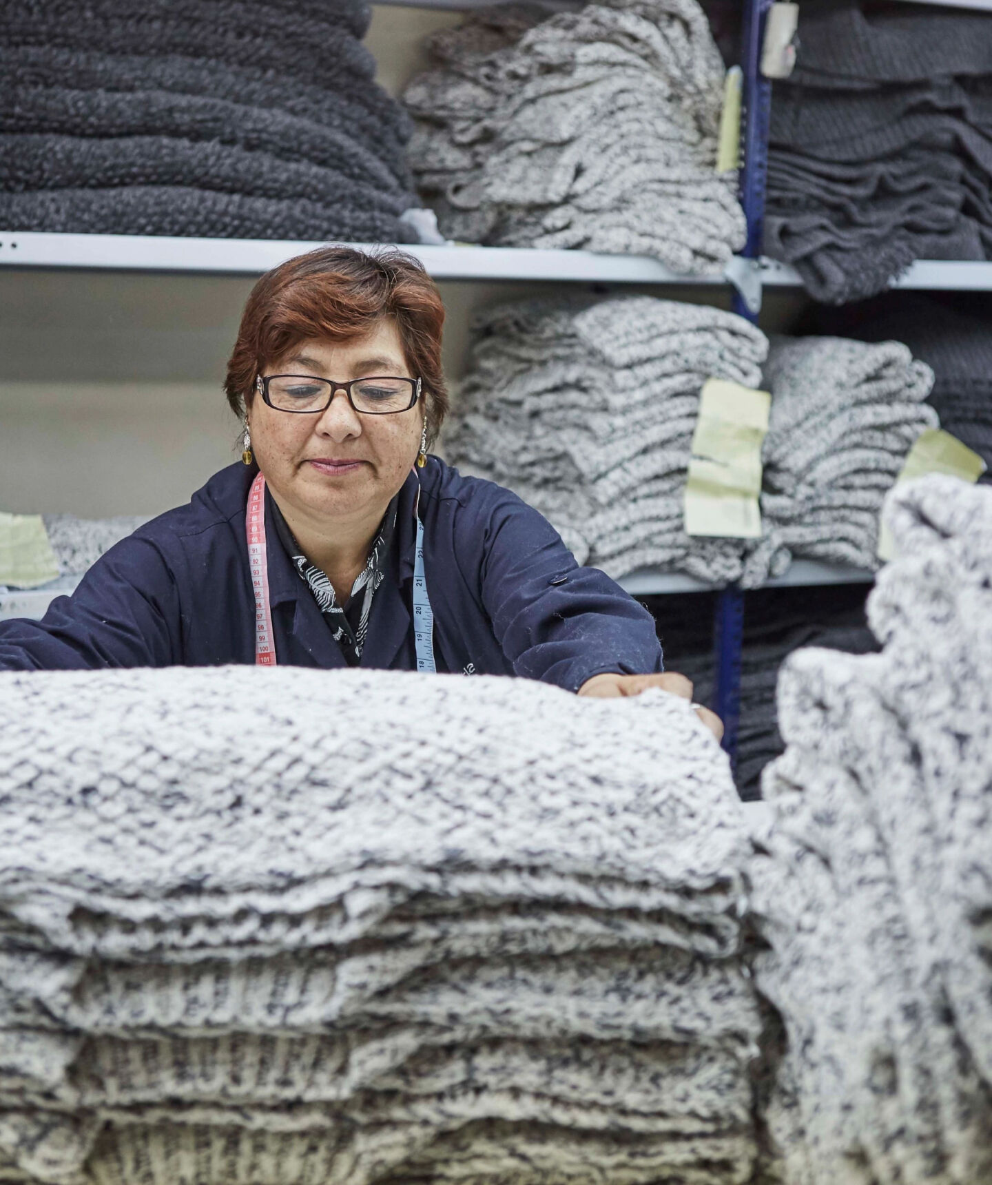 Woman folding sweaters at a knit factory.