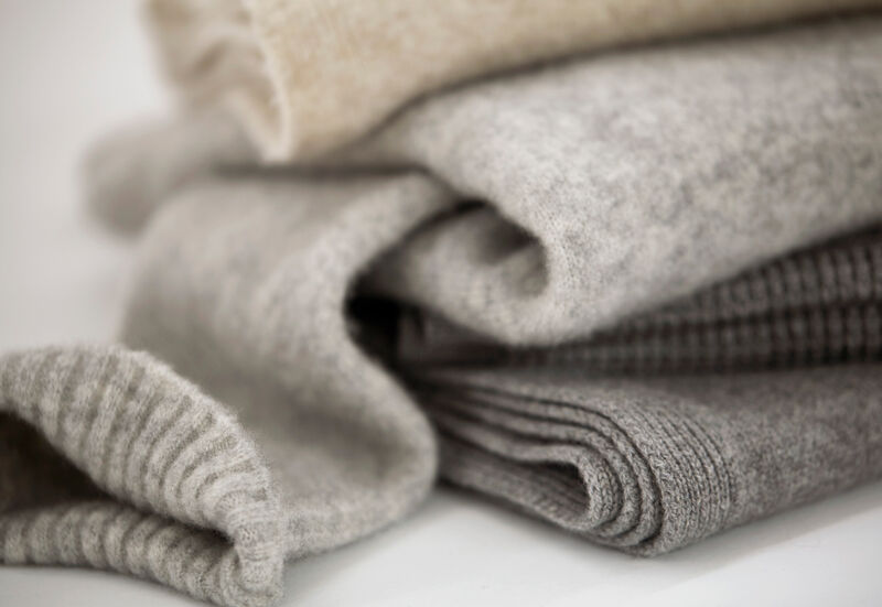 A stack of women's cashmere and merino sweaters in neutral colors from EILEEN FISHER