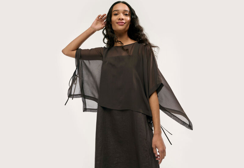Woman wearing linen dress and silk poncho.
