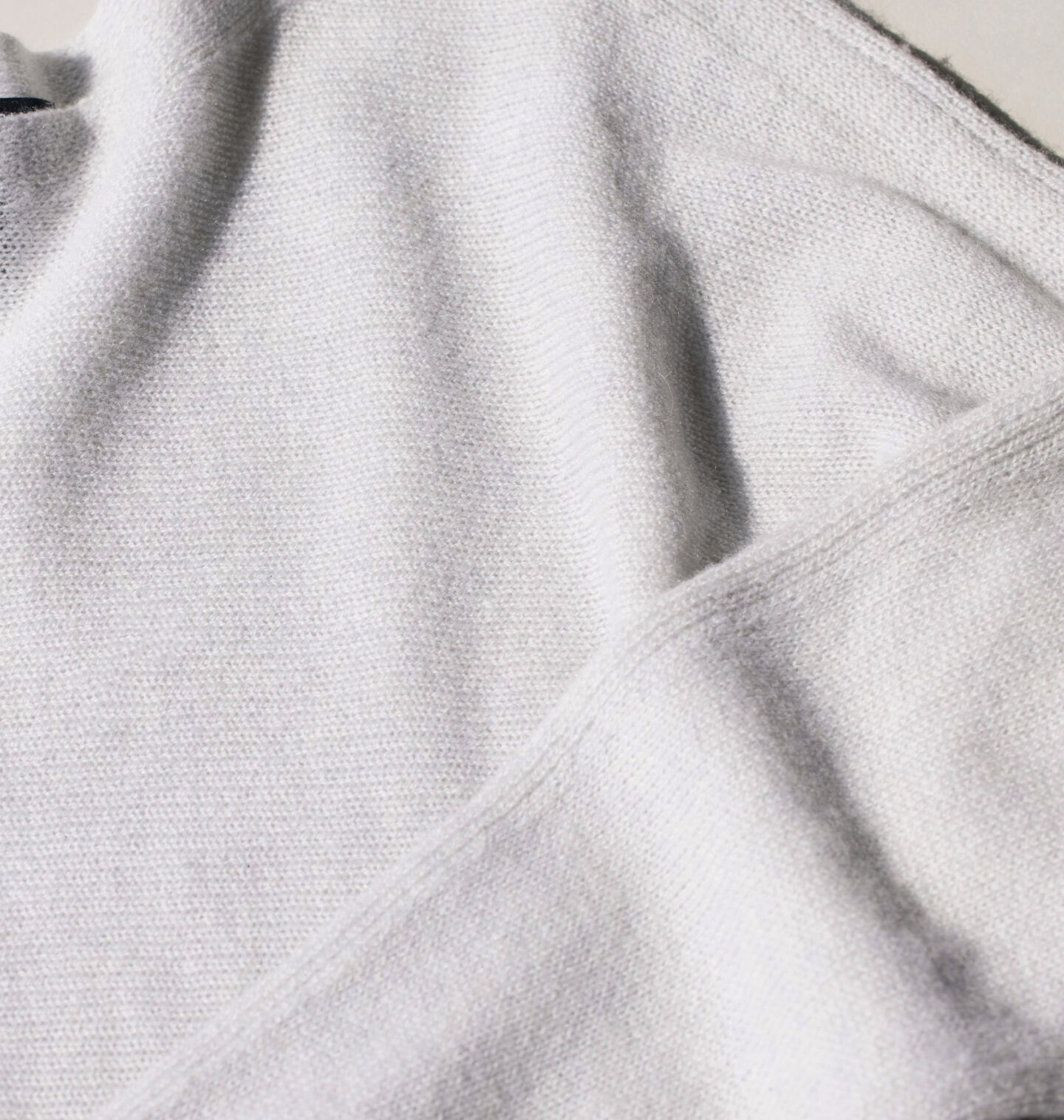 A woman's white knit sweater laid flat.