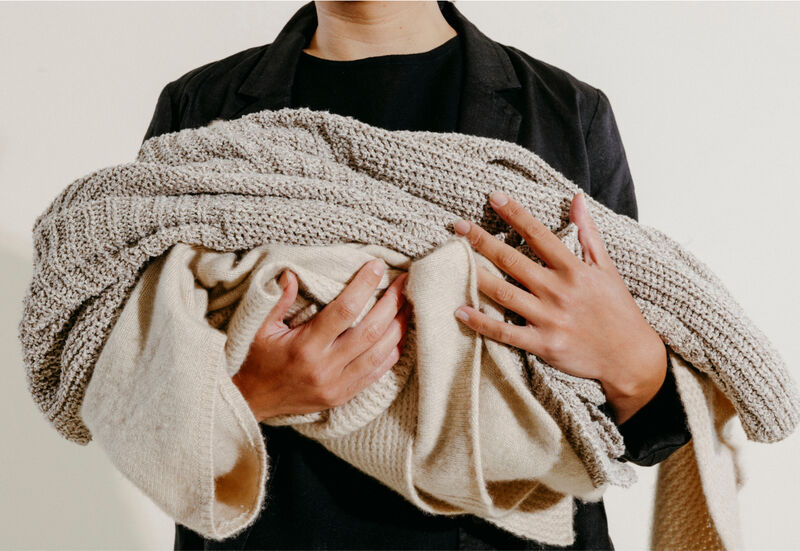 A woman holding clothes from EILEEN FISHER's take-back program, Renew.