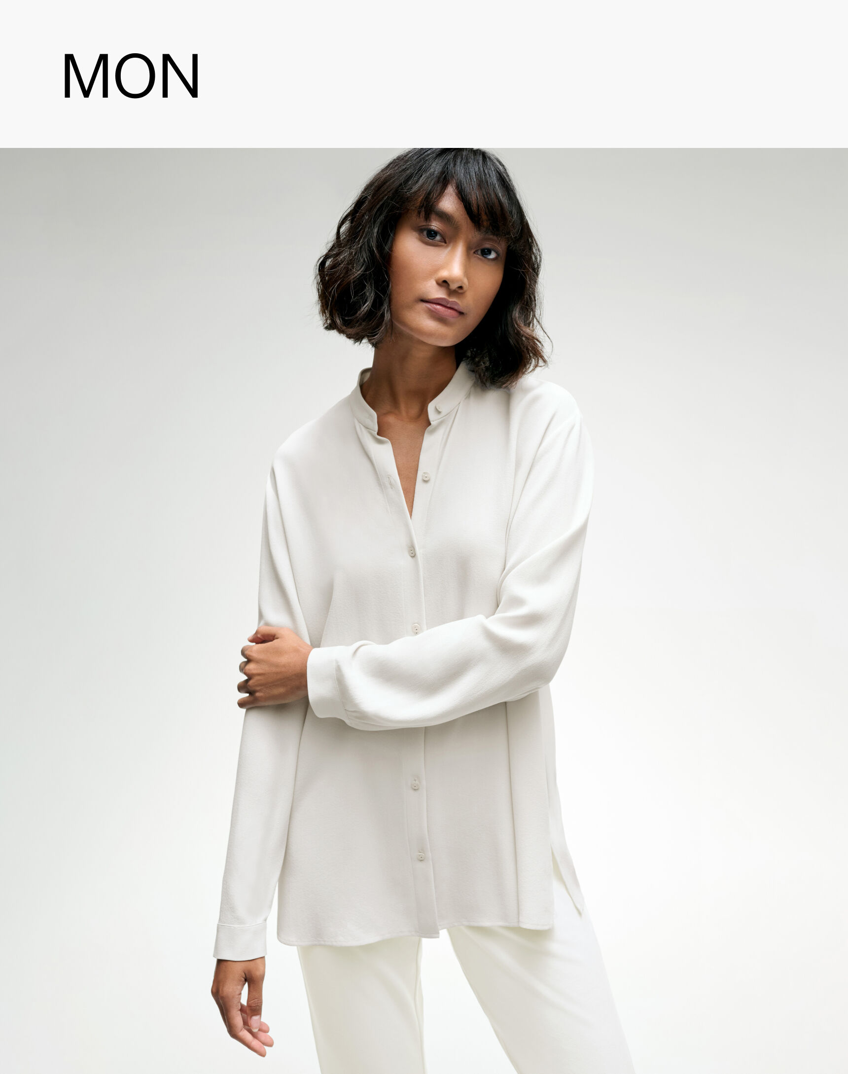 Woman dressed for work in white silk button-down shirt from EILEEN FISHER.