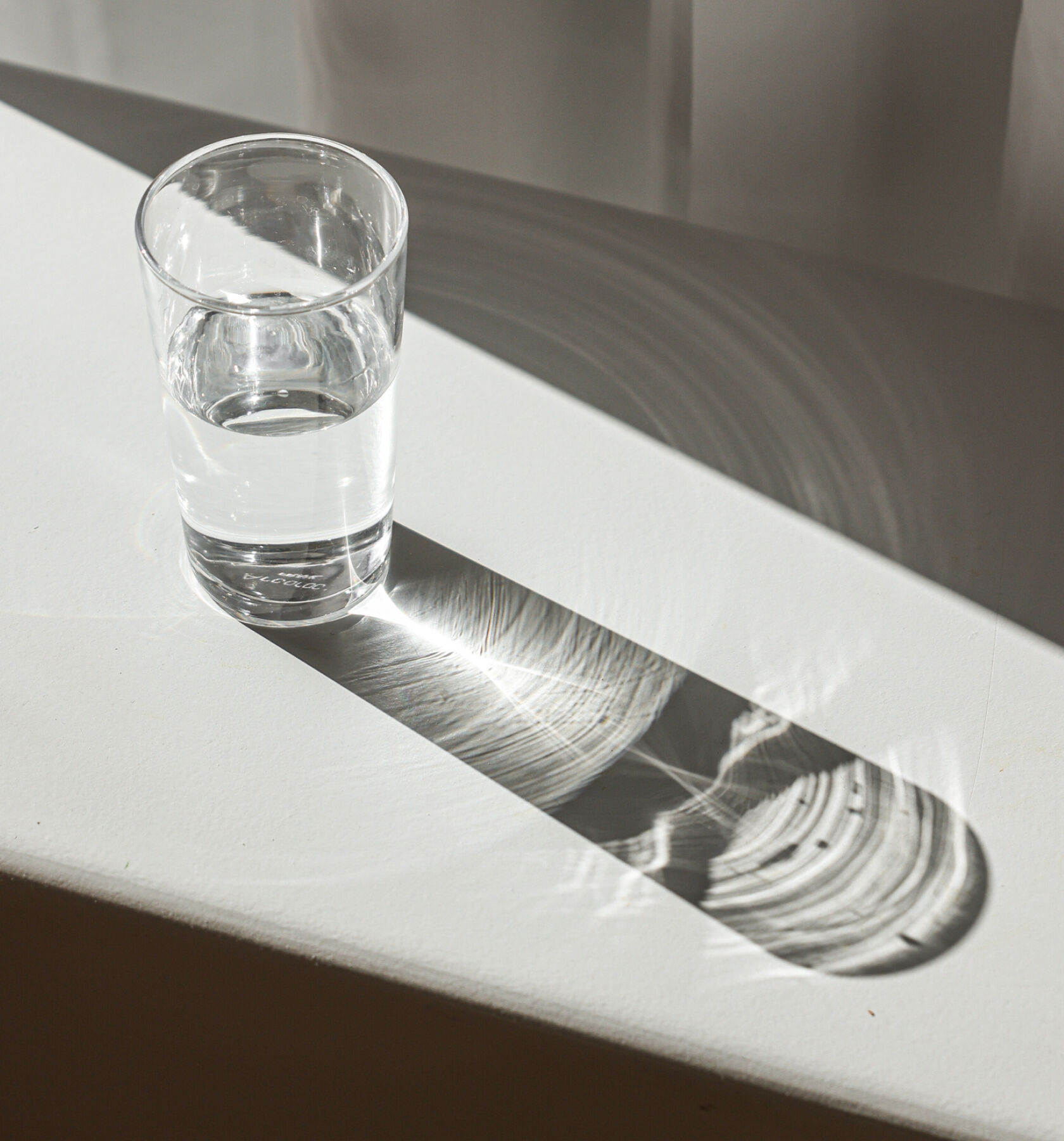 A glass of water on a white table. A glass of water on a white table.
