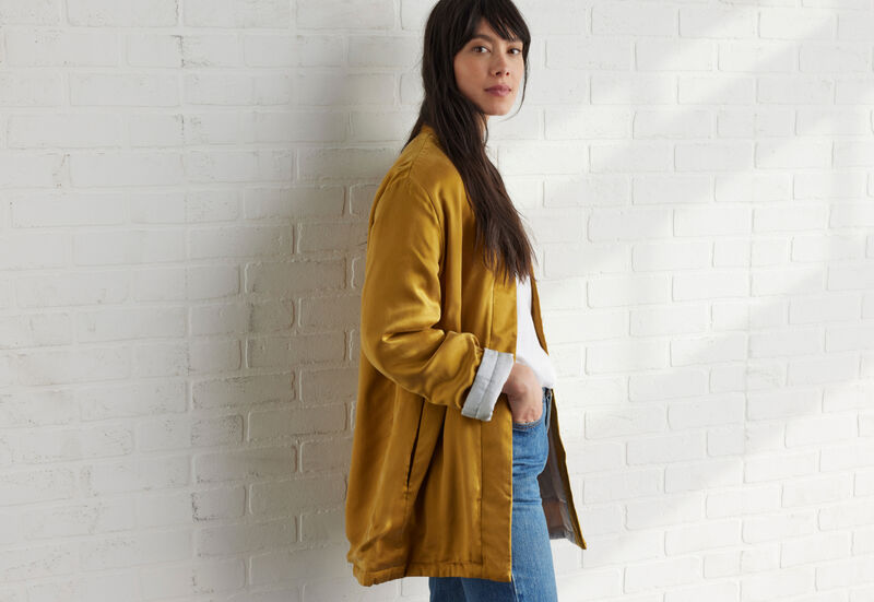 Woman wearing a timeless yellow silk jacket by EILEEN FISHER.