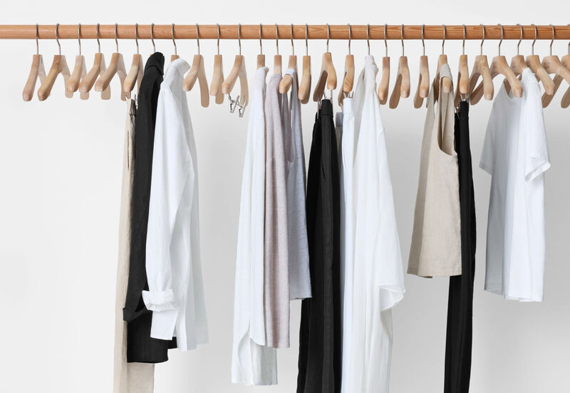 Clothing rack with a few simple pieces on wooden hangers.