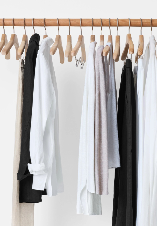 Clothing rack with a few simple pieces on wooden hangers.