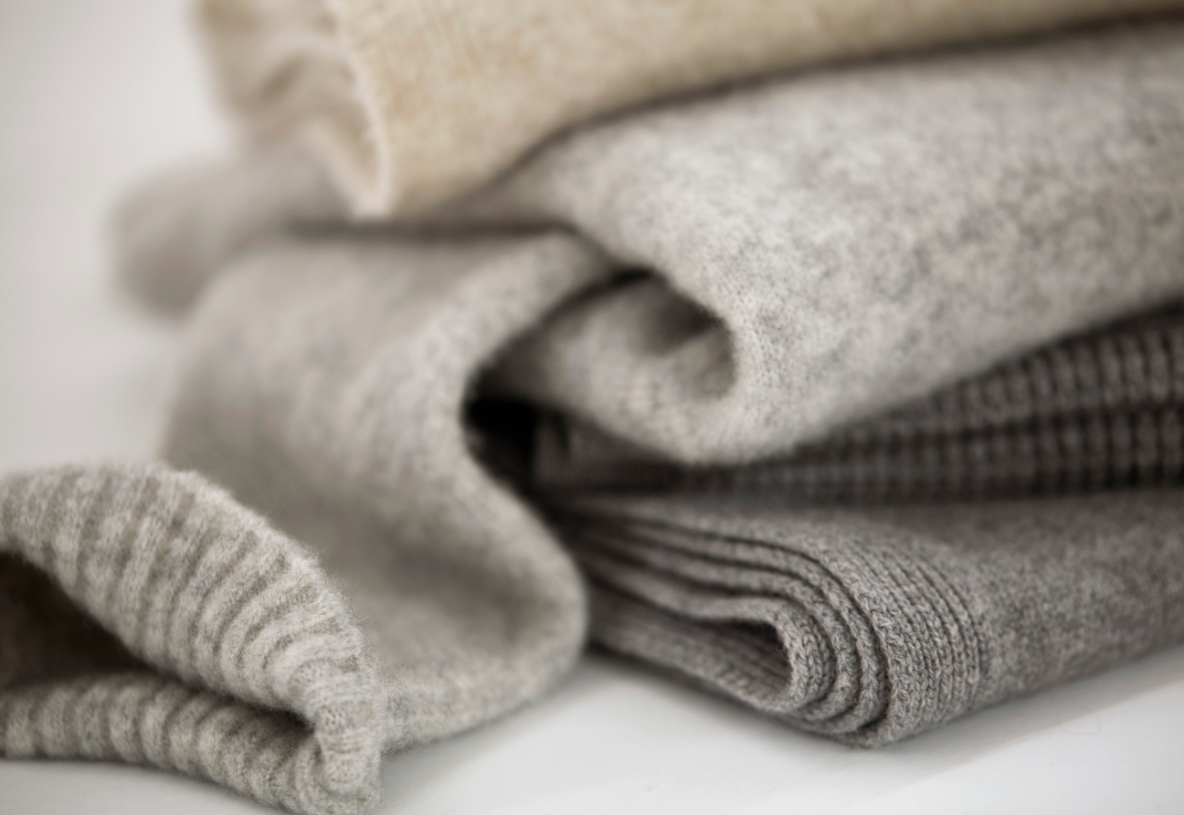 A stack of women's cashmere and merino sweaters in neutral colors from EILEEN FISHER