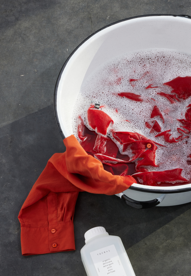 Orange silk shirt being hand washed in a basin.